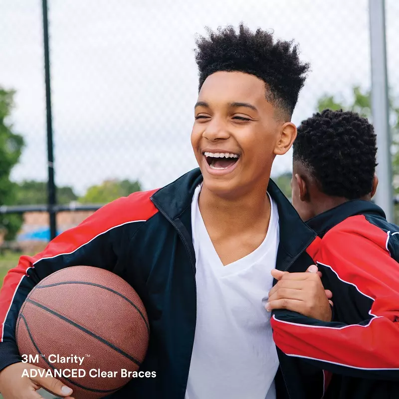 A young man holding onto a basketball while laughing.