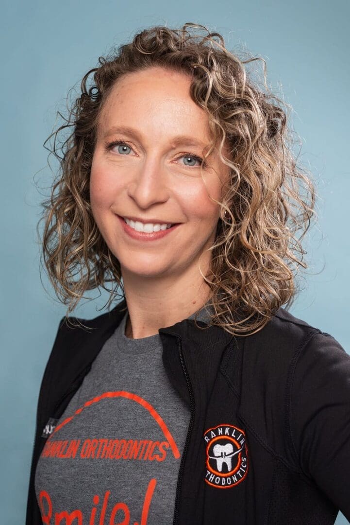 A woman with curly hair and a gray shirt.