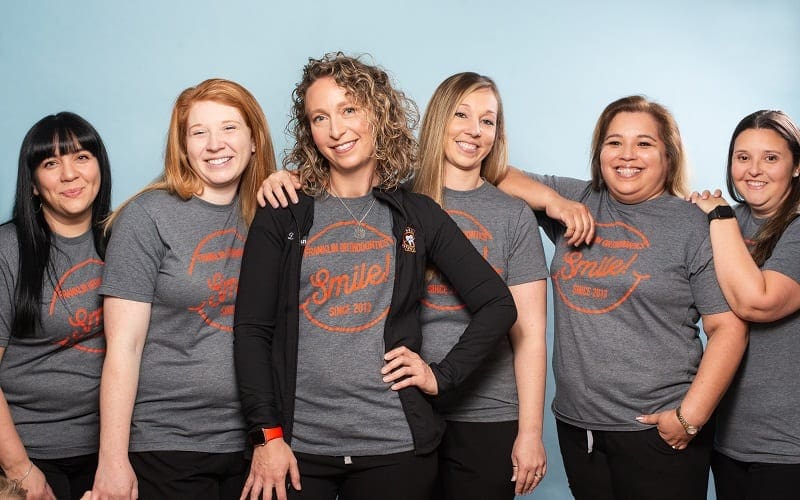 A group of women wearing grey shirts and black pants.